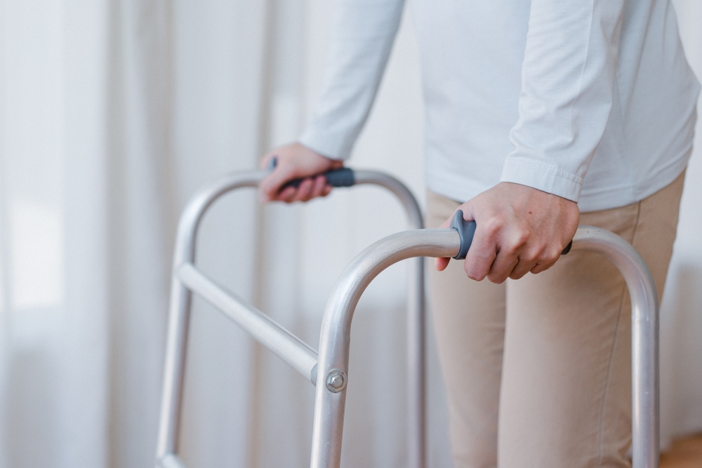 Cropped,view,of,elderly,man,walking,with,frame,at,home,