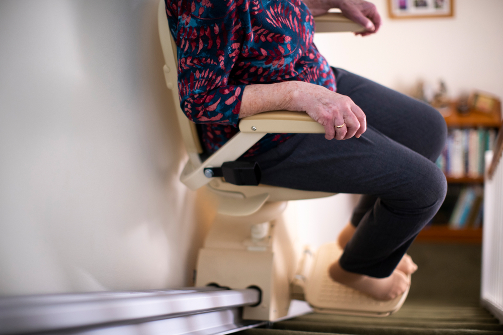 Detail,of,senior,woman,sitting,on,stair,lift,at,home
