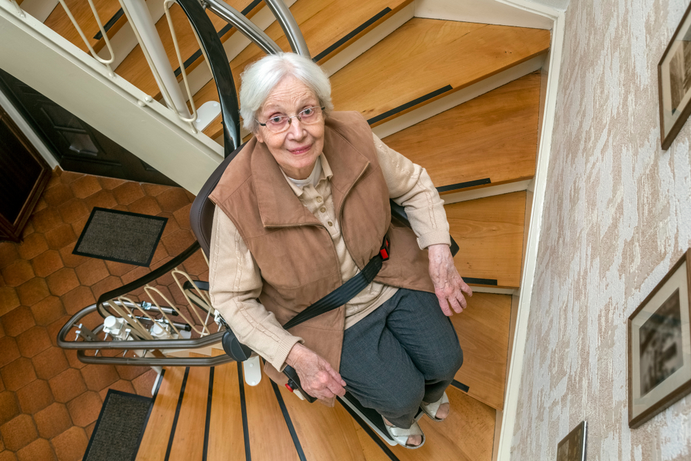 Elderly,woman,in,the,staircase,using,the,stairlift